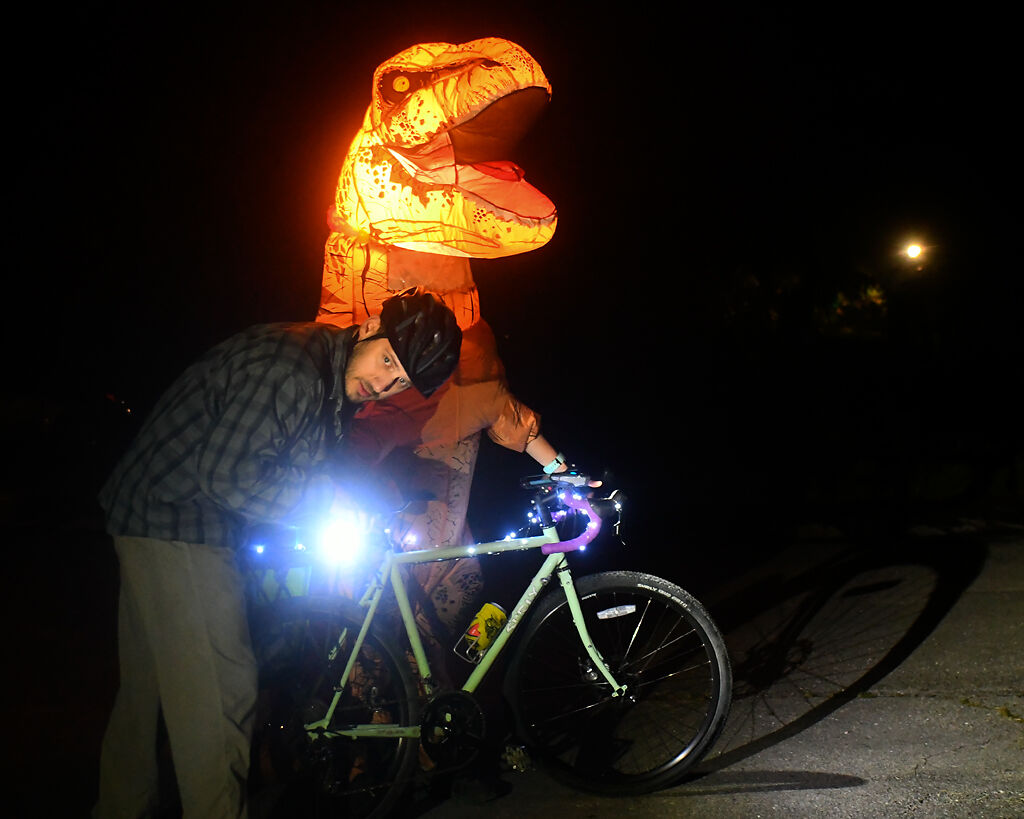 From left, Paul Bird helps Laurel Hill with her lights on her bike Saturday at Twin Lakes Park in Columbia.